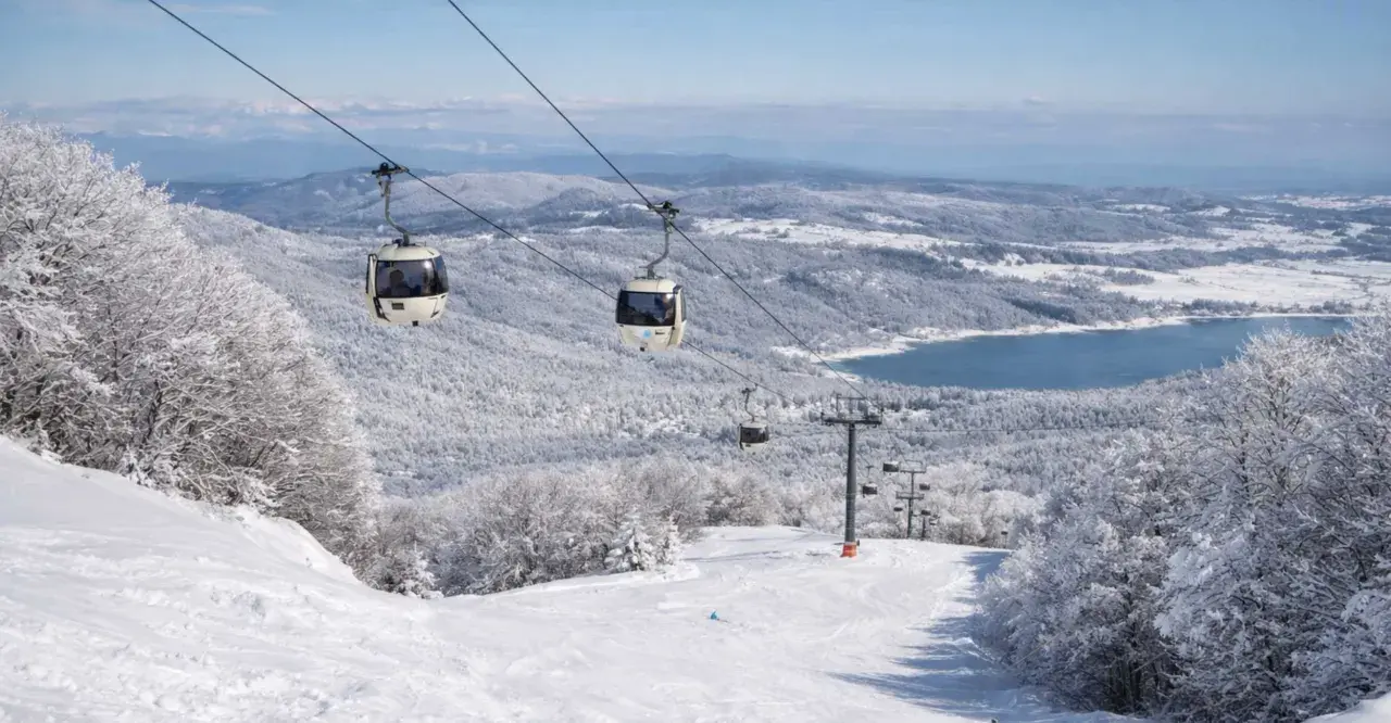 Funivia su montagne innevate, un lago azzurro sullo sfondo. Scopri dove sciare in Calabria per un'esperienza indimenticabile.