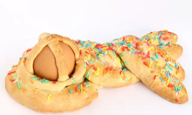 Dolci calabresi pasquali: un uovo incastonato in una treccia di pane dolce, decorata con zuccherini colorati.