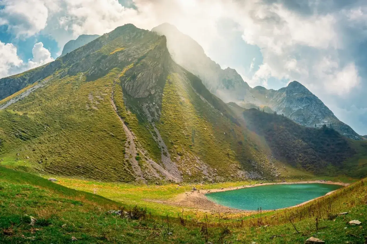 Lago alpino turchese incastonato tra montagne verdi, perfetto per un trekking Lombardia in giornata.