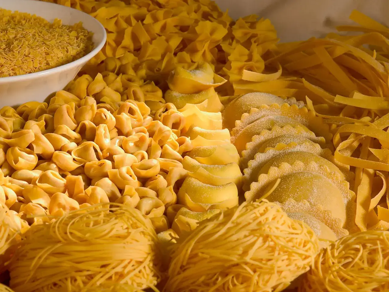 Variet&agrave; di pasta fresca, tra cui tortellini, ravioli e tagliatelle, che rappresentano i cibi tipici dell'Emilia Romagna.