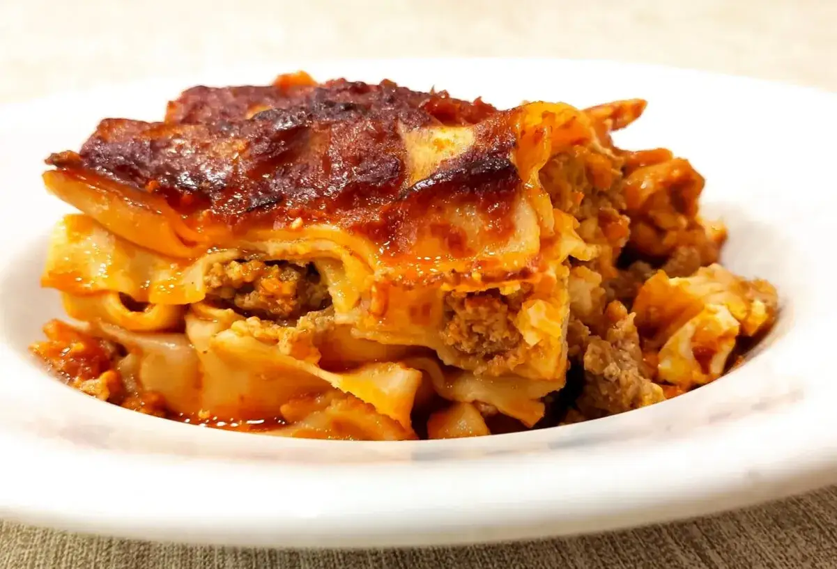 Porzione di lasagna al rag&ugrave;, uno dei piatti tipici di Avellino, servita su un piatto bianco.