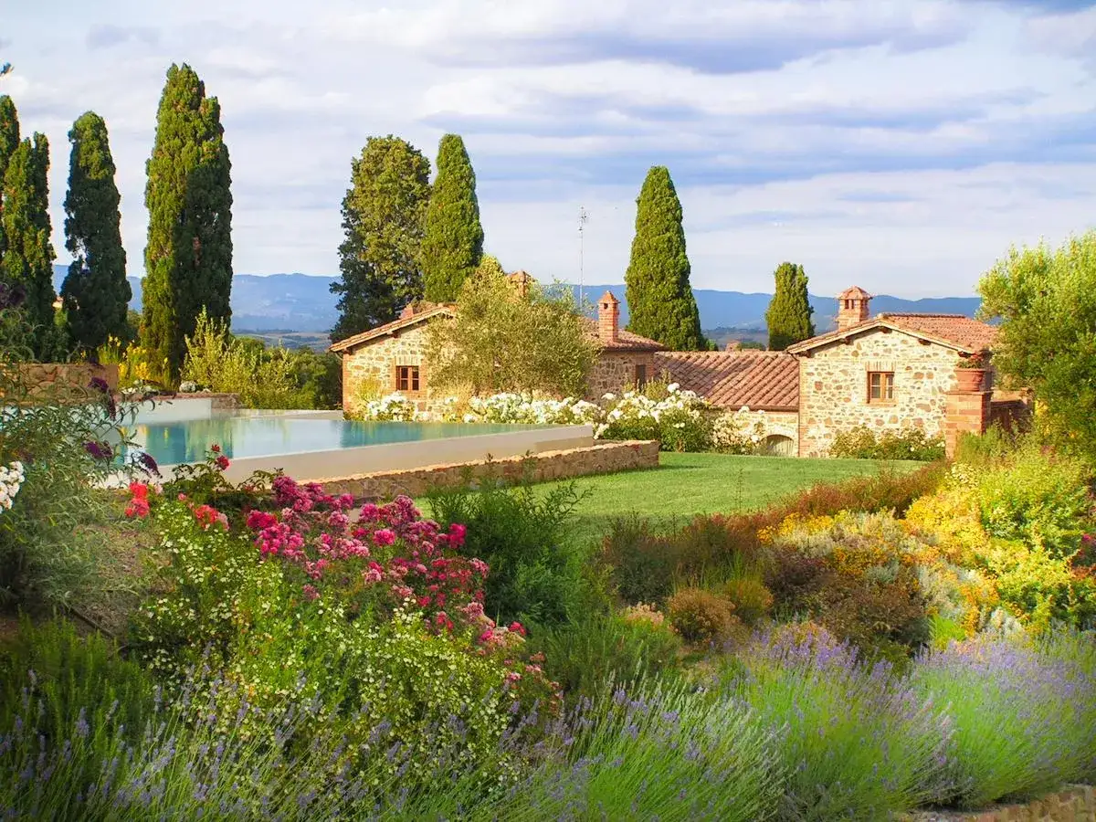 Un sogno di vacanze in Toscana: piscina, casali in pietra e un giardino fiorito che invita al relax.