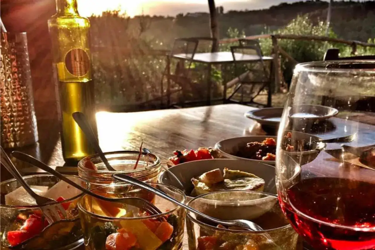 Un delizioso weekend in Toscana: antipasti, vino rosso e tramonto su un tavolo all'aperto.