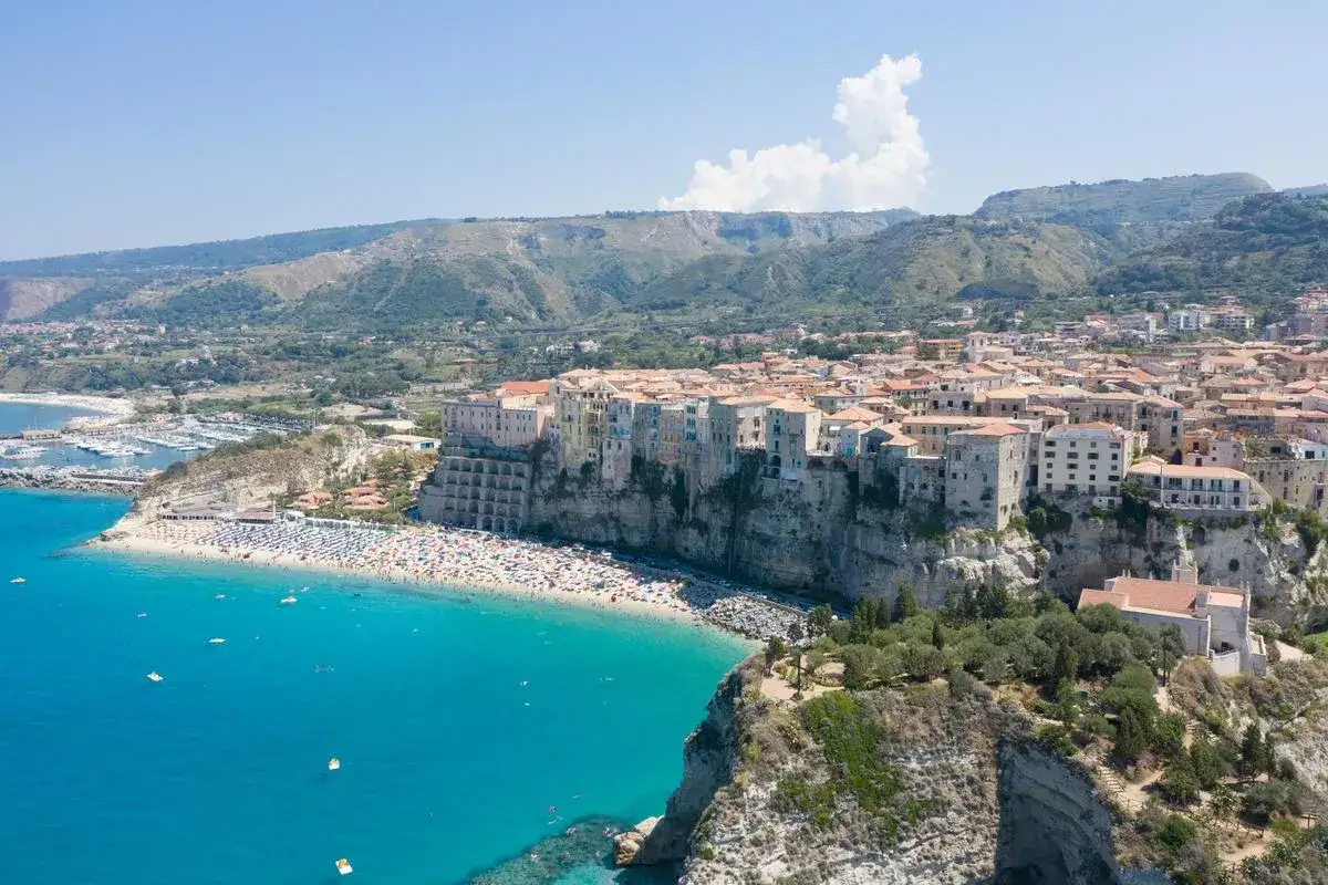 Tropea, gioiello della Calabria, con il suo borgo arroccato sulla scogliera e la spiaggia affollata. Curiosità sulla Calabria: un luogo da sogno.