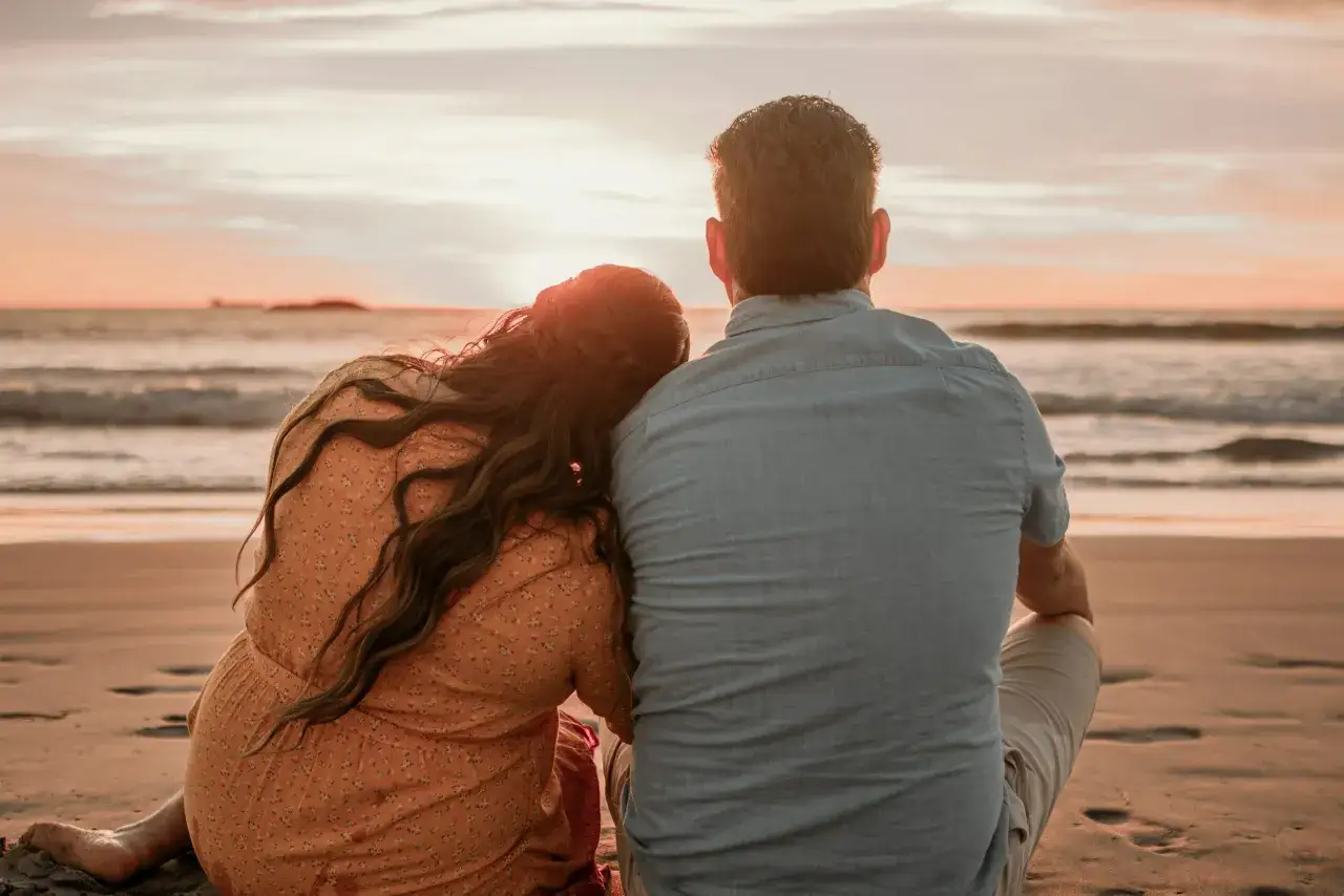 Coppia abbracciata sulla spiaggia al tramonto, un momento perfetto per una vacanza romantica.