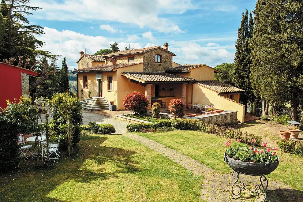 Un casale toscano immerso nel verde, perfetto per capire dove andare in vacanza in Italia. Un sogno tra cipressi e tulipani.