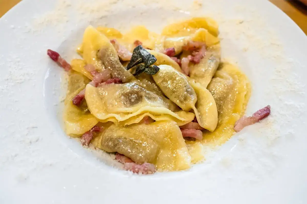 Ravioli ripieni con pancetta e salvia, un piatto tipico bergamasco, spolverati di formaggio grattugiato.