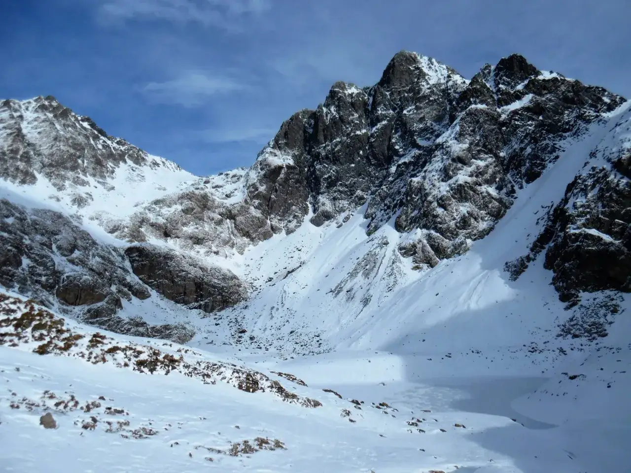 Vette innevate e un lago ghiacciato, il lago del diavolo, sotto un cielo azzurro e nuvoloso.